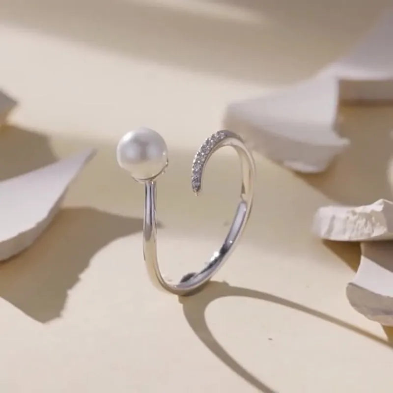 Silver adjustable open loop ring with shell pearls on white background