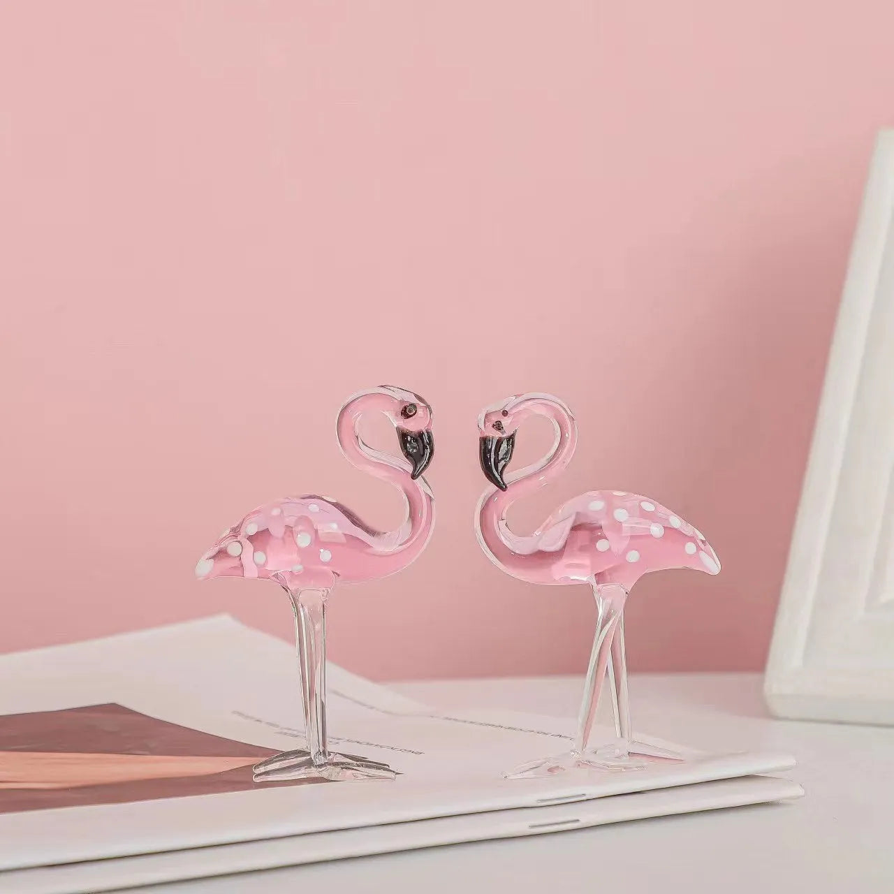 A pink flamingo decorative ornament made from clear white crystal on a table.