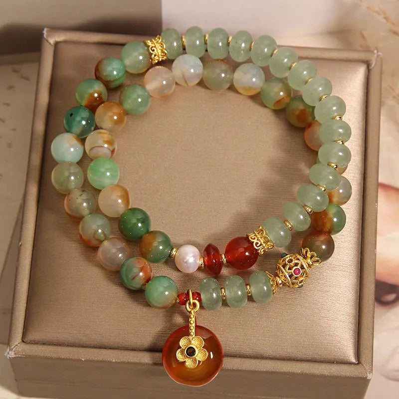 Gold-toned double ring chain bracelet with a peacock green agate safety buckle pendant and rhinestone details.