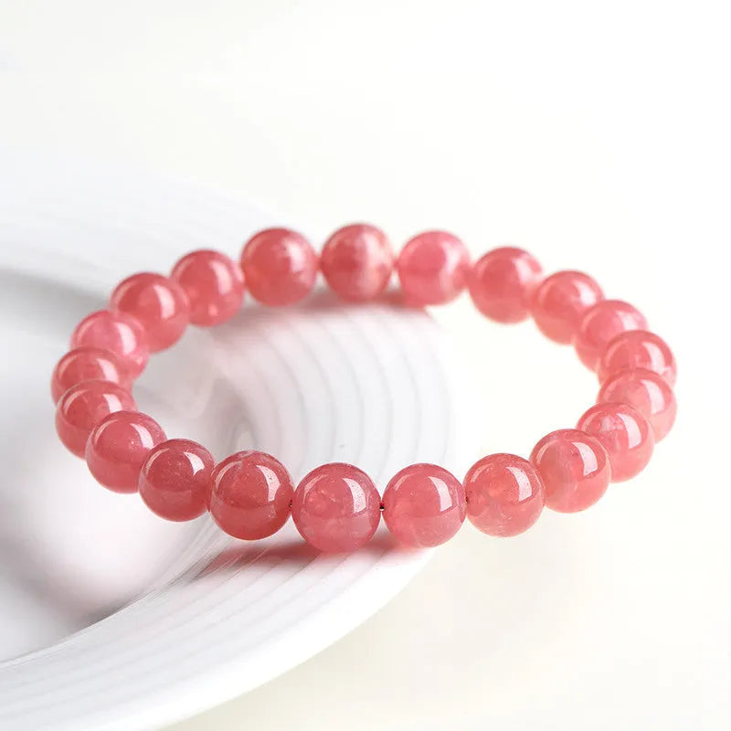 Women's red rhodochrosite crystal bracelet with geometric beads and longevity lock charm on wrist