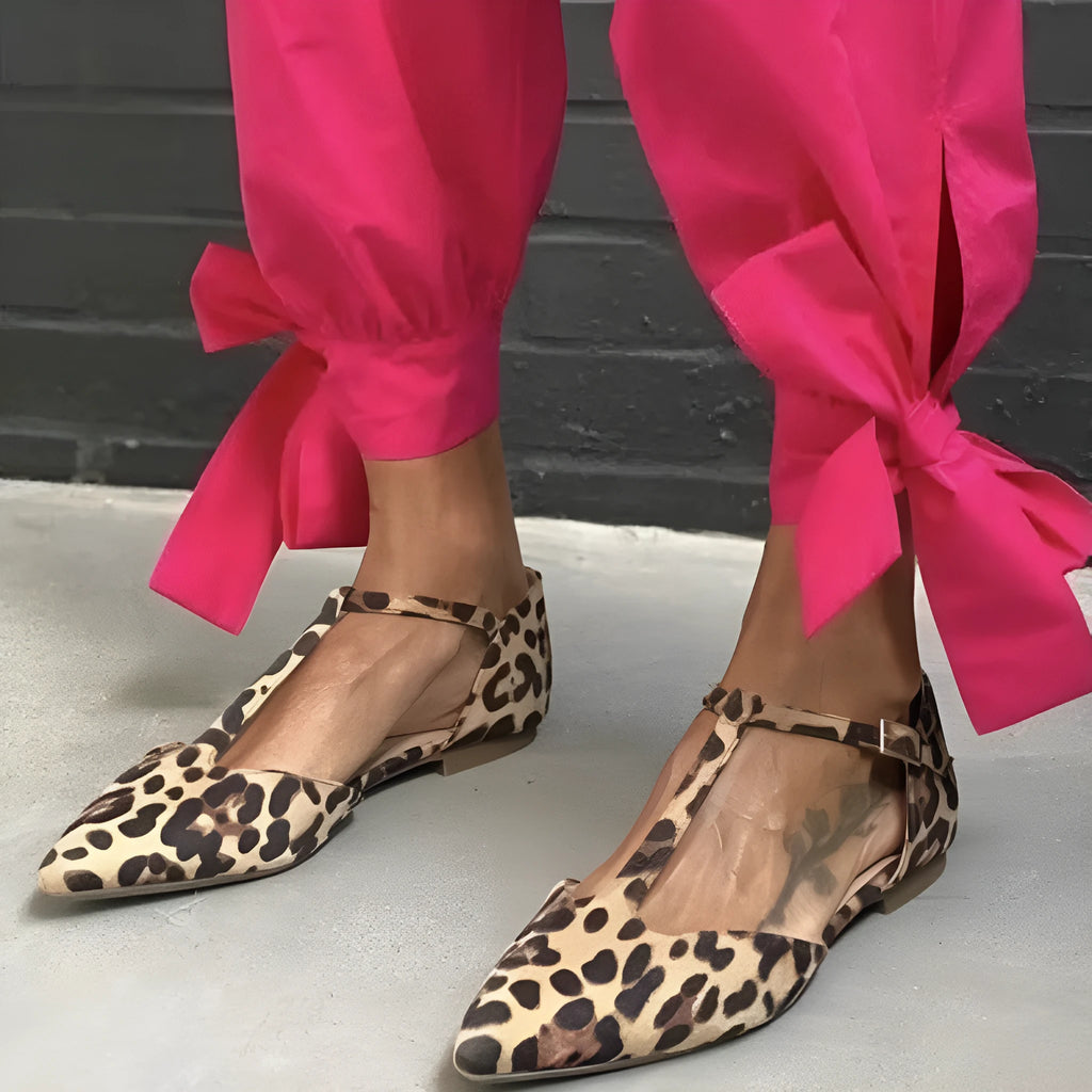 Women's low-top leopard print pumps with a chunky heel and cross shoulder straps on a pointed toe.