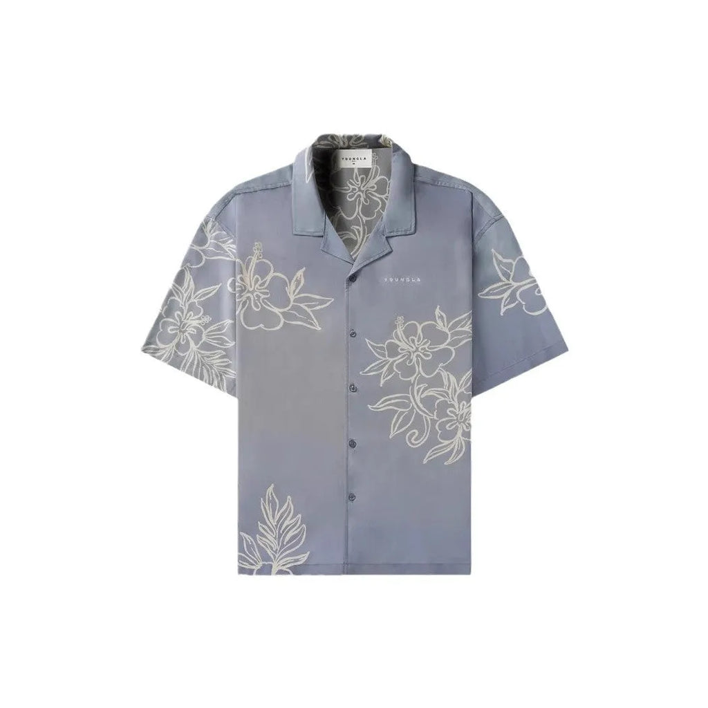 Man wearing a loose-fitting grey short-sleeve top with a floral print design.