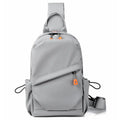 Men's black polyester crossbody bag with a single shoulder strap, shown in a casual setting.
