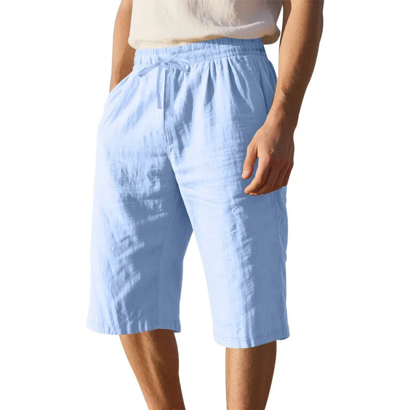 Man wearing loose, cropped linen shorts in a solid colour with a drawstring waist.
