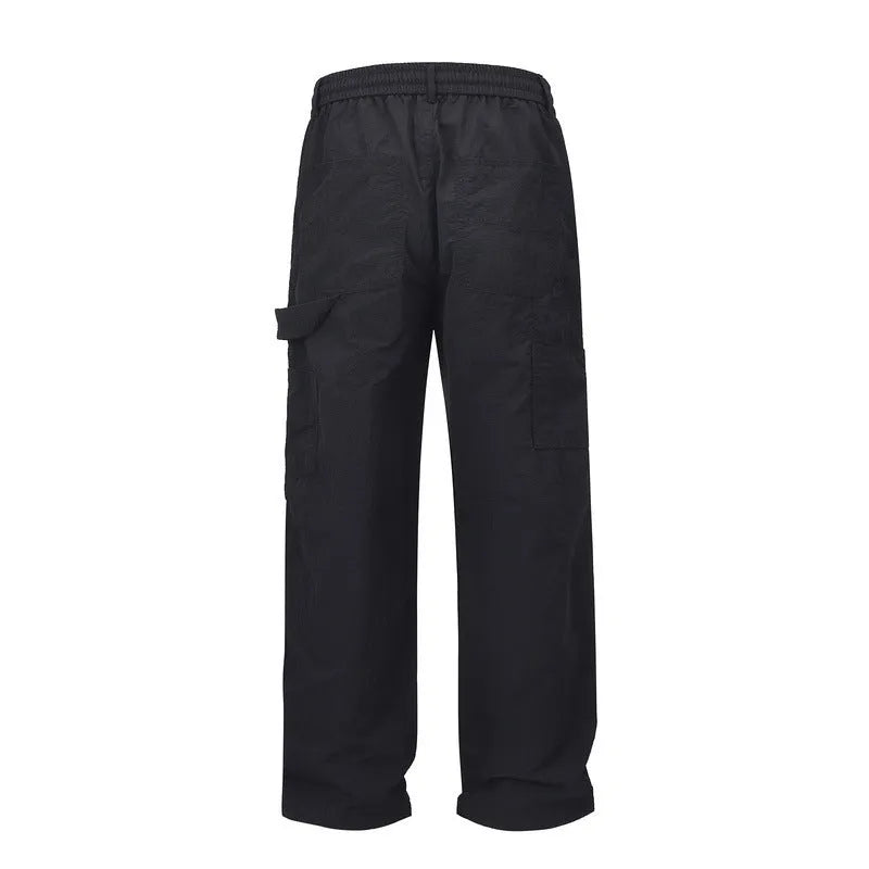 Black baggy paratrooper trousers with an elasticated drawstring waistband and three-dimensional cutting.