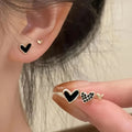 Three pairs of women's alloy heart-shaped earrings in gold, black, black-white, and pink colours