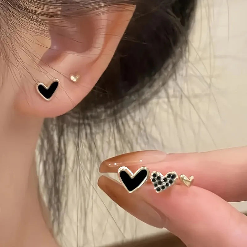 Three pairs of women's alloy heart-shaped earrings in gold, black, black-white, and pink colours
