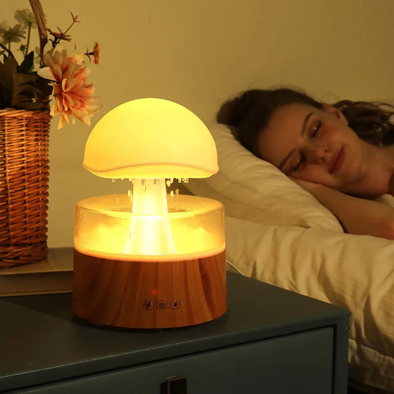 White rain cloud shaped ultrasonic humidifier and aromatherapy diffuser with coloured lights on a wooden table.