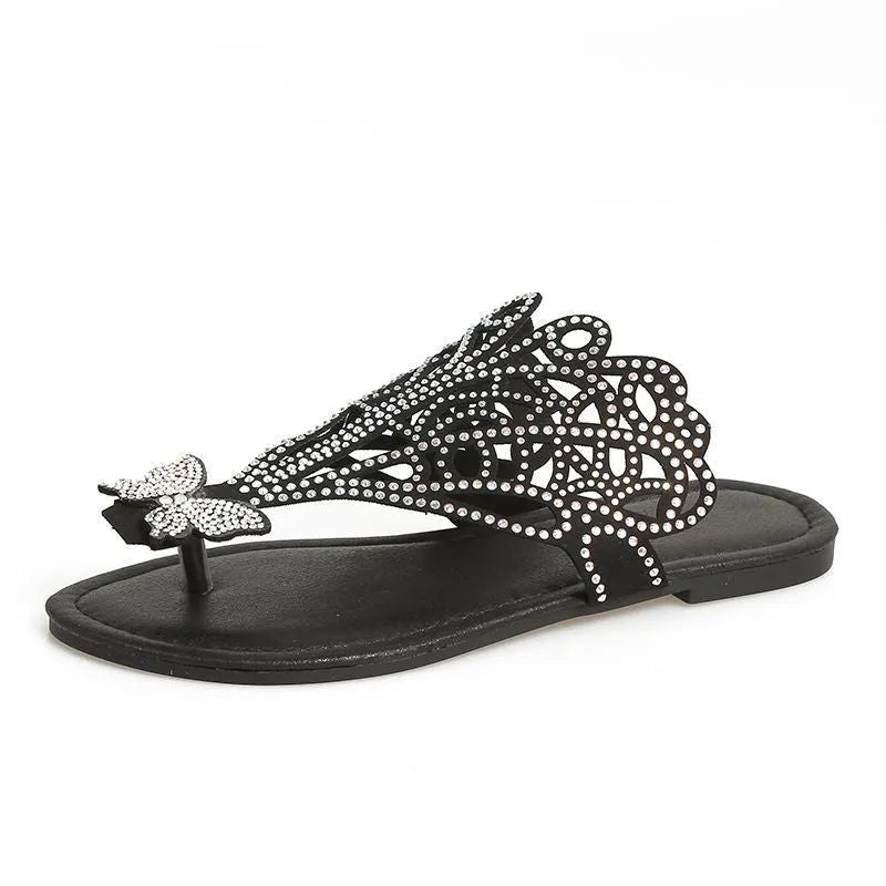 Women's black slip-on sandals with rhinestone decoration and a flip-toe design on a light background.