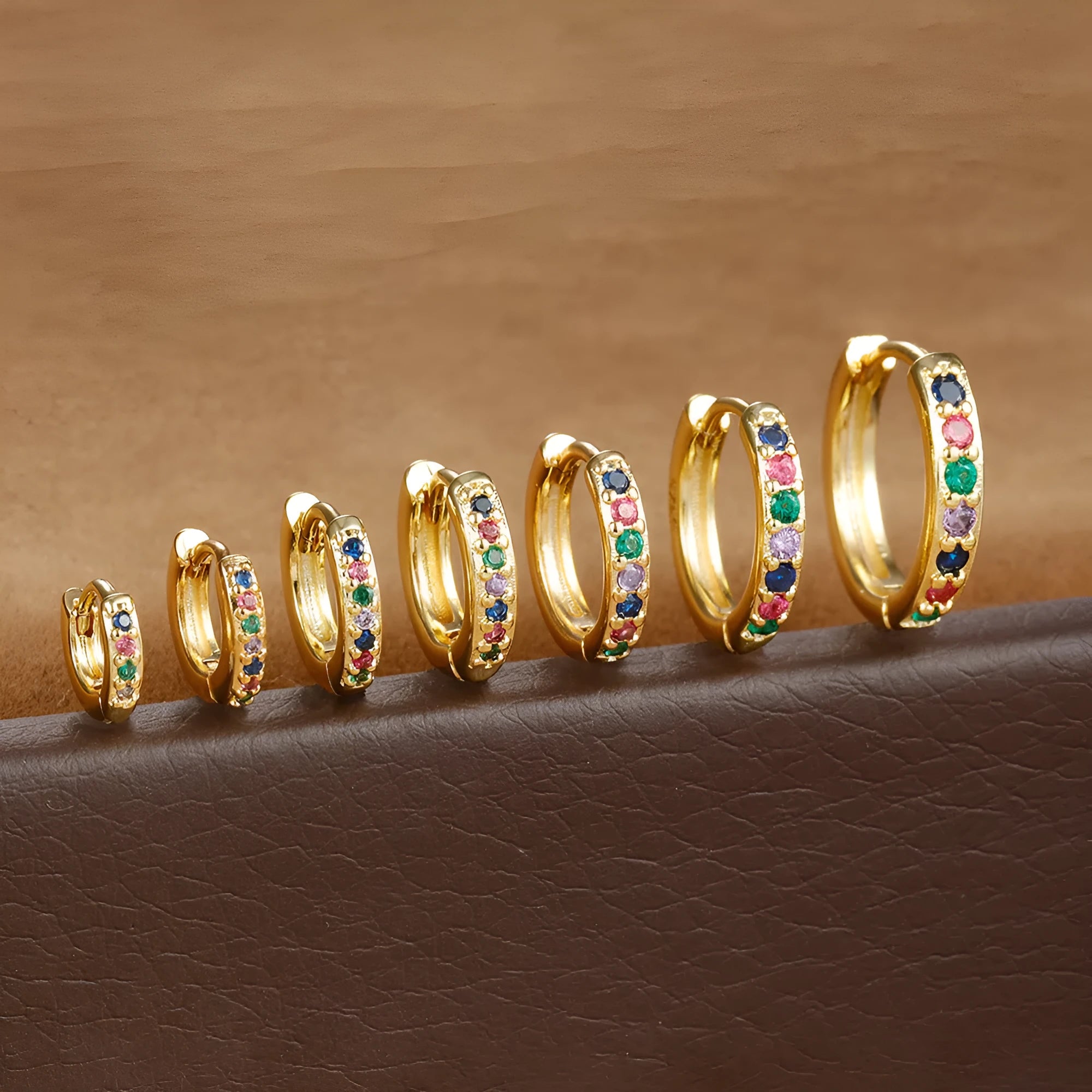Gold, rose gold, and silver colour perforated circle zircon stud earrings in various sizes on a white background.