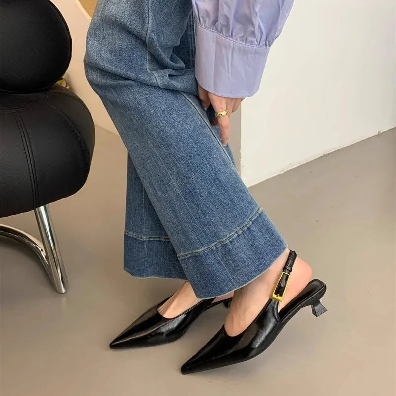 Women's black low heel pointed leather court shoe with an ankle strap on a rubber sole.