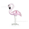 A pink flamingo decorative ornament made from clear white crystal on a table.