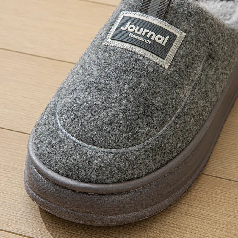 Men's brown suede slippers with a thickened design and textured EVA sole, shown on a wooden floor.