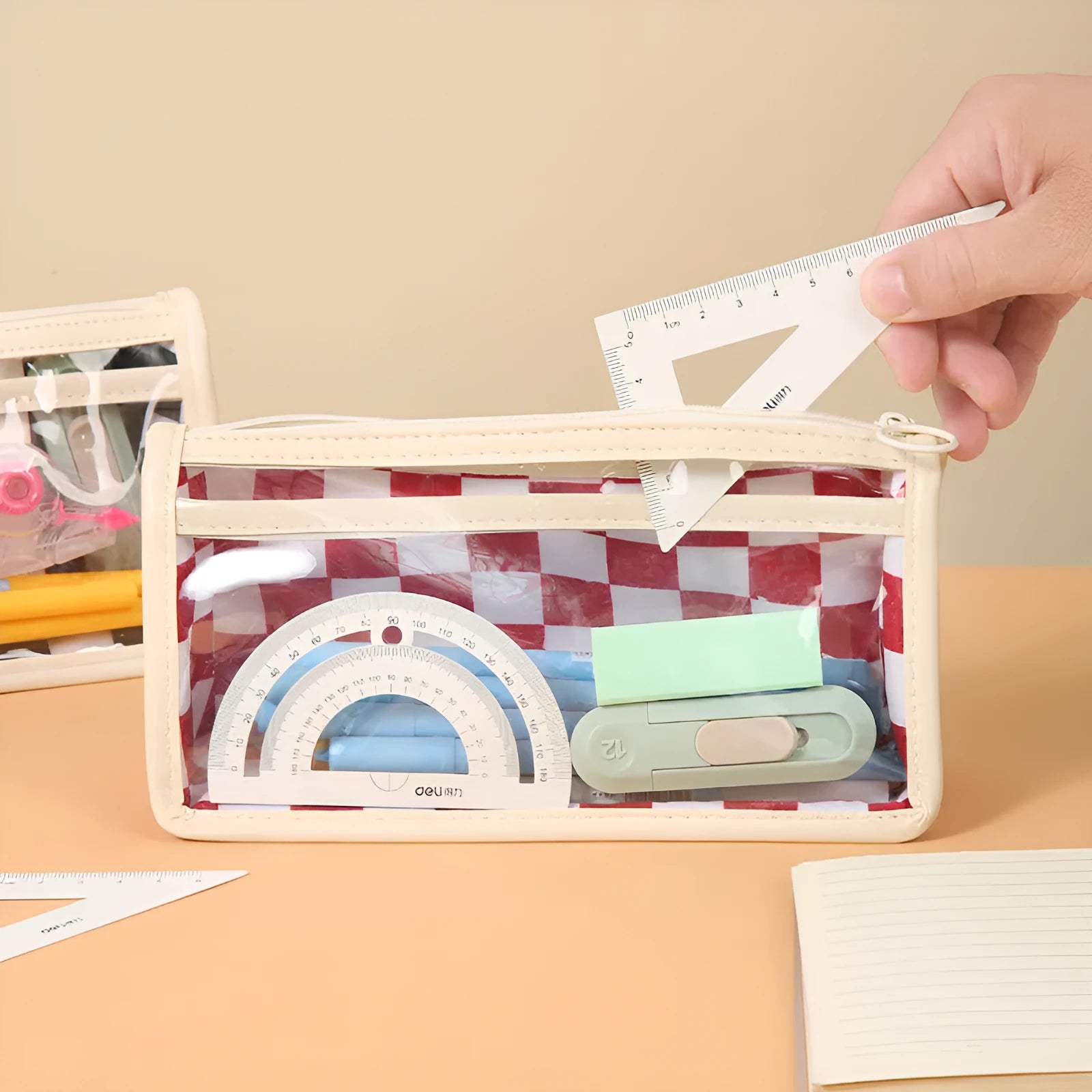 Transparent PVC pencil case showing internal chessboard grid pattern, measuring 21.5cm long.