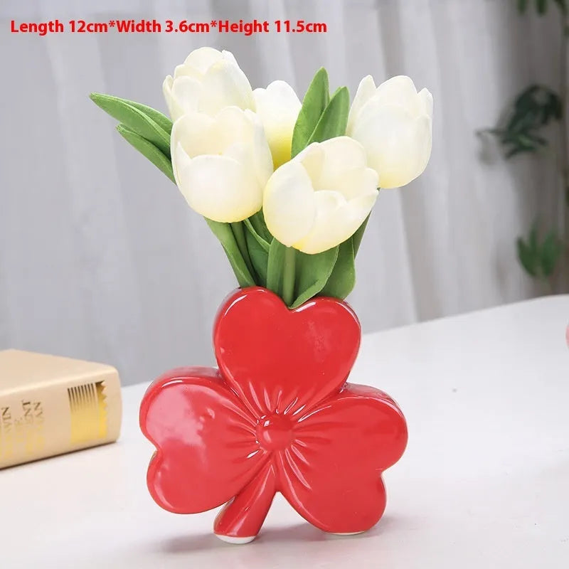 Small clover-design ceramic vase in pink, red, light green, or white on a desktop.