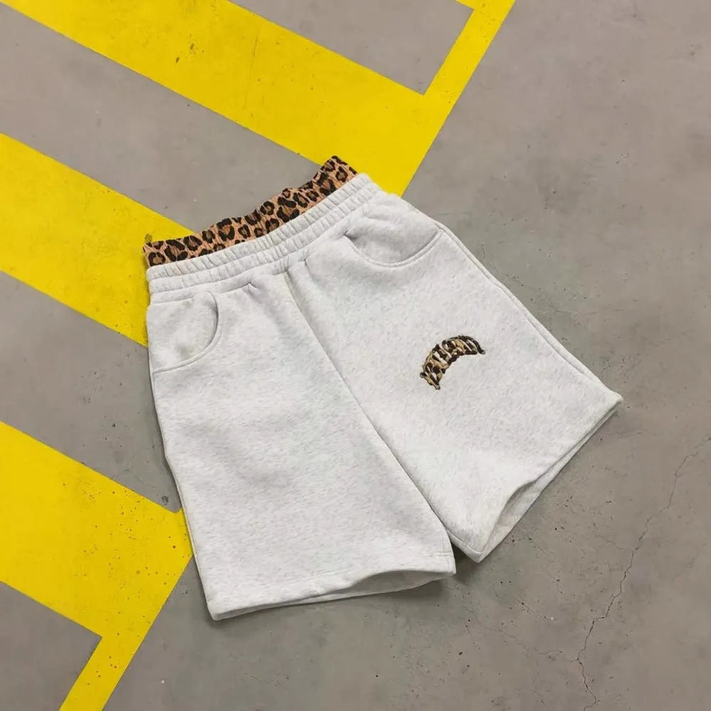 Men's grey loose trousers featuring a patchwork double waist design and a zip fly.