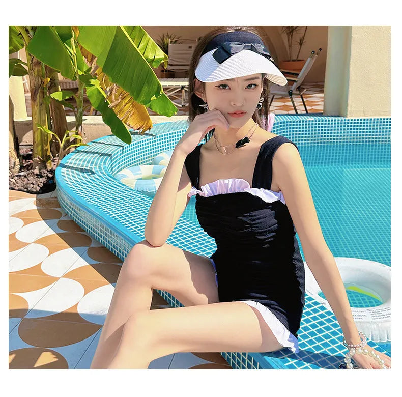 Women's black one-piece swimsuit with suspender straps, polyester fabric, solid colour design