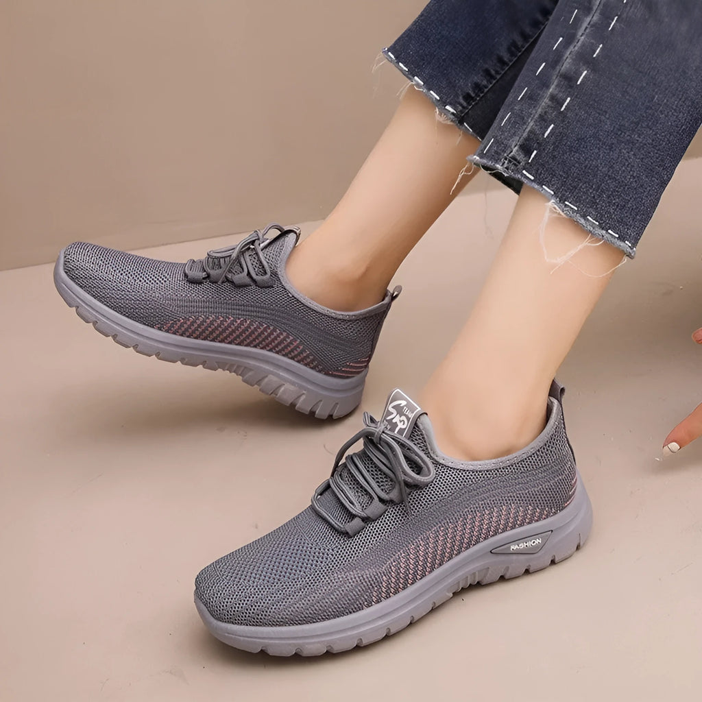 Women's black mesh sneakers with round toe and cross strap detail on rubber sole