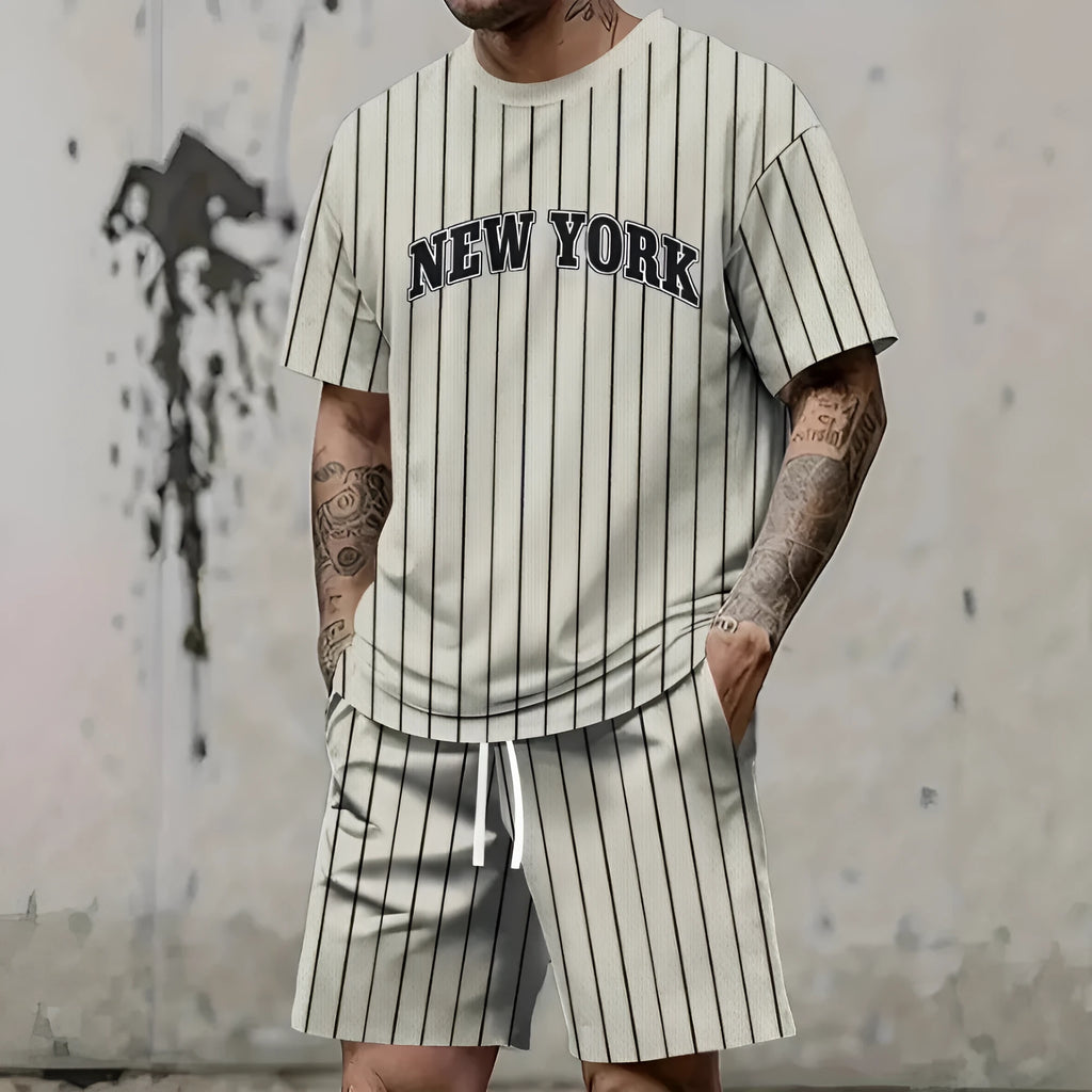 Man wearing a grey short sleeve top and matching shorts with a 3D printed white letter design.