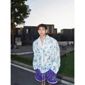 Pink loose fit floral long sleeve shirt with embossed three-dimensional pattern on a hanger.
