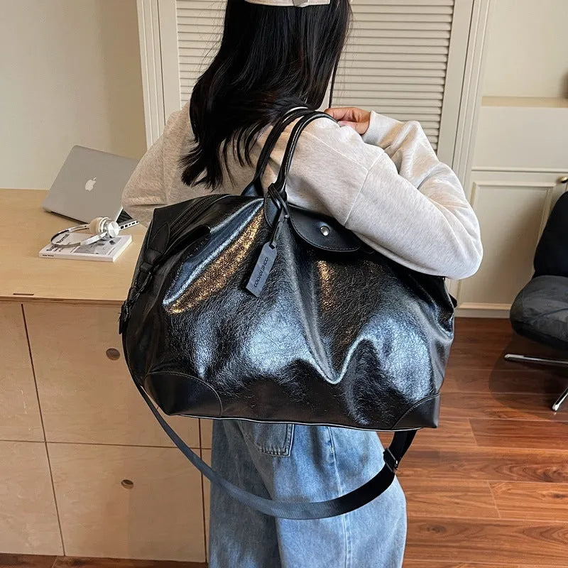 Women's hand-carry travel bag in black or silver with 36-55 litre capacity and PU material construction