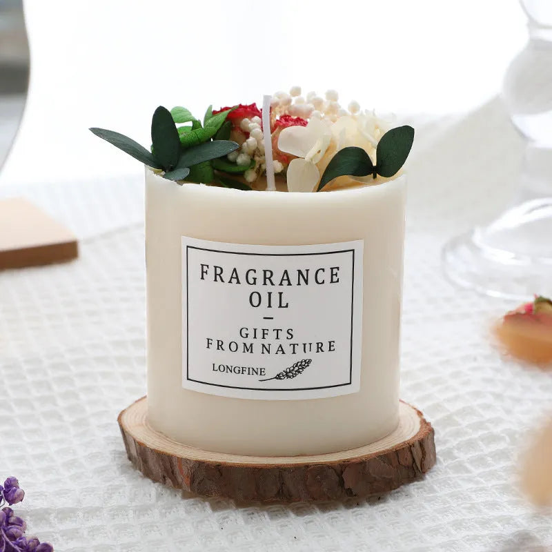 Decorative scented candle with dried flowers inside, shown with wood chip base and gift box.