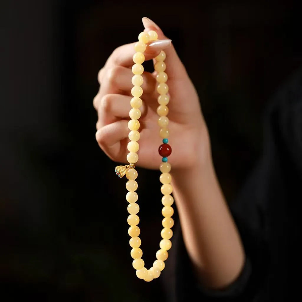 Yellow jade double ring bracelet with topaz lotus seedpod design on white background
