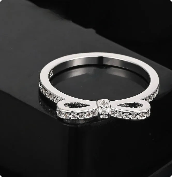 Silver couple ring with a bow shape set with rhinestones and zircon crystals.