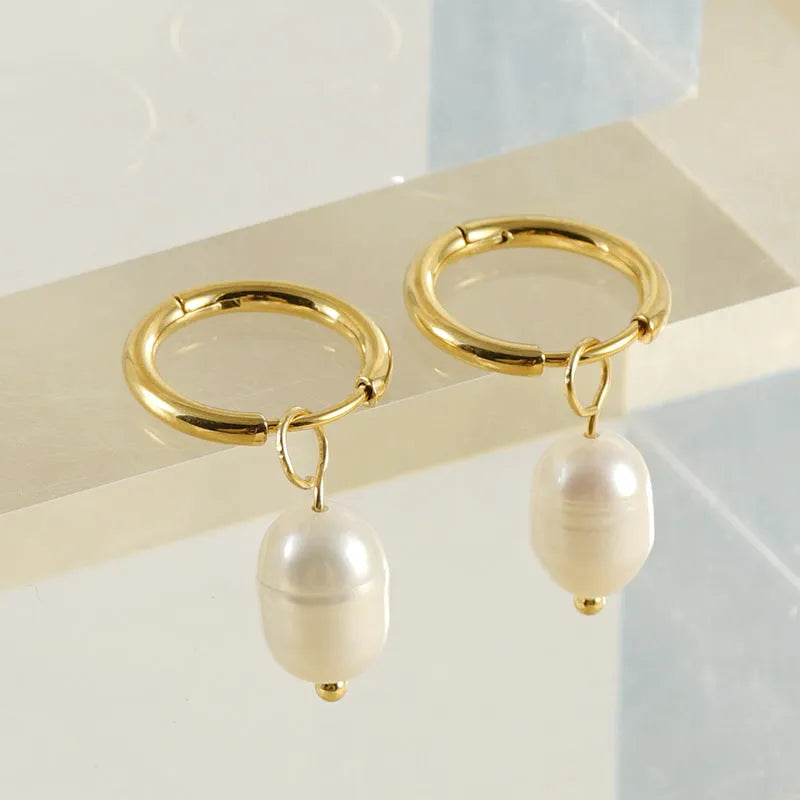 A pair of gold geometric earrings with pearl details on stainless steel and titanium steel posts.