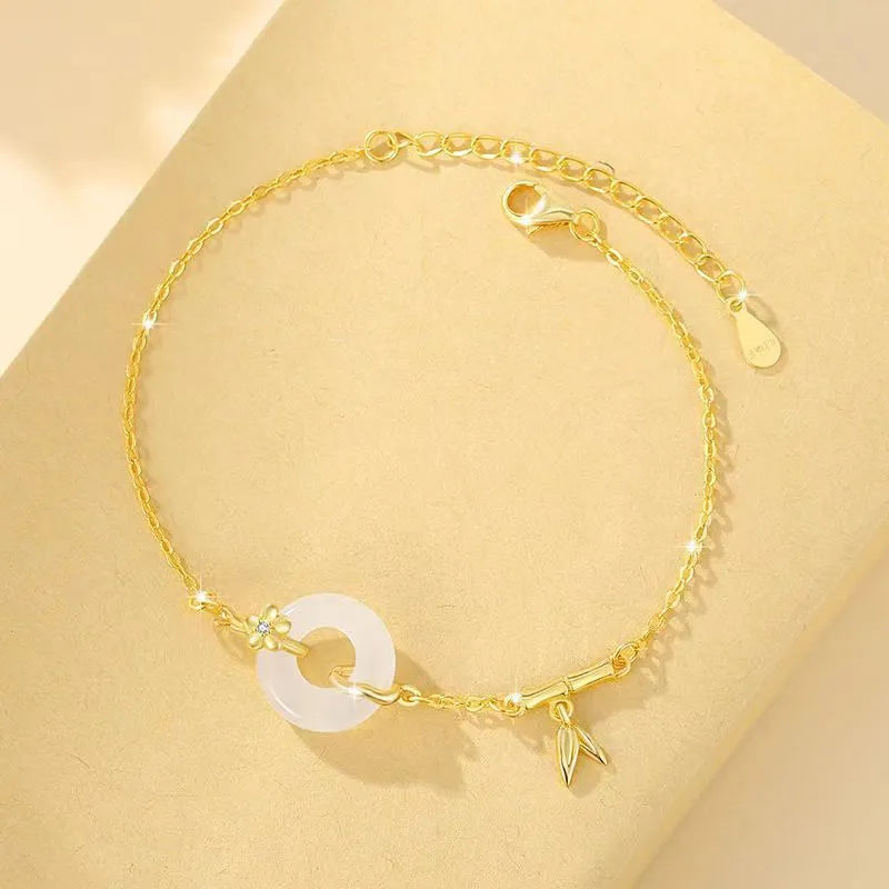 Gold-coloured women's silver bracelet with a peace buckle design and white chalcedony stone centrepiece.