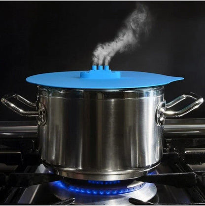 A silicone cooking lid with a ship-inspired design, featuring a three-port steam release system and a convenient hook for easy storage.