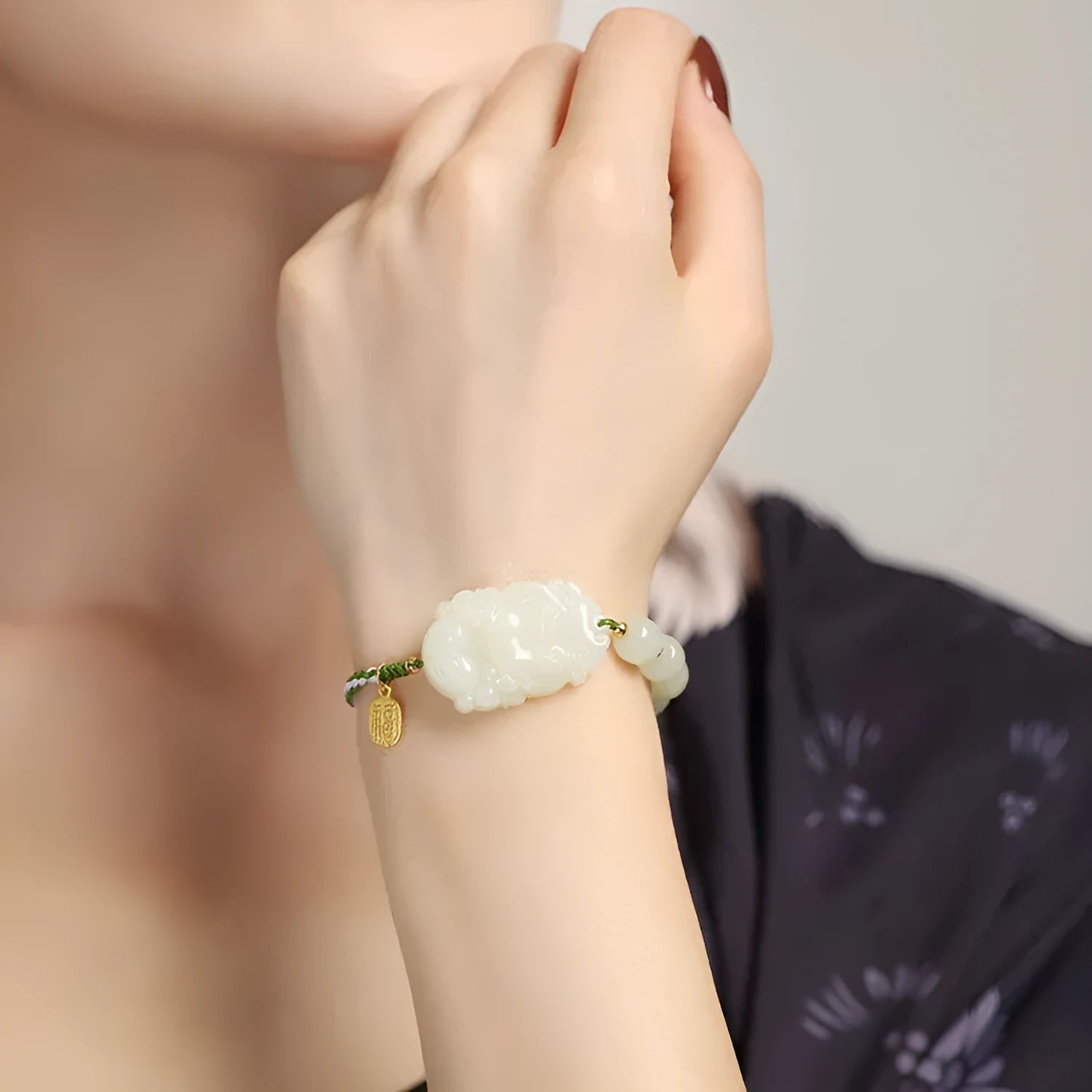 Year of the Rabbit red cord bracelet with Hetian jade charm and small silver blessing card.