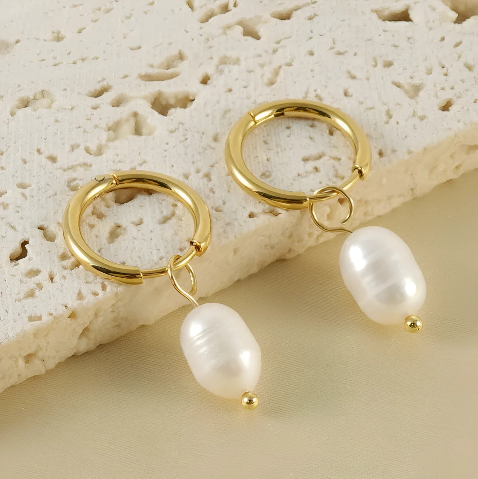 A pair of gold geometric earrings with pearl details on stainless steel and titanium steel posts.
