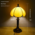 Modern minimalist beige coloured bedside lamp with a width of 20cm on a table.