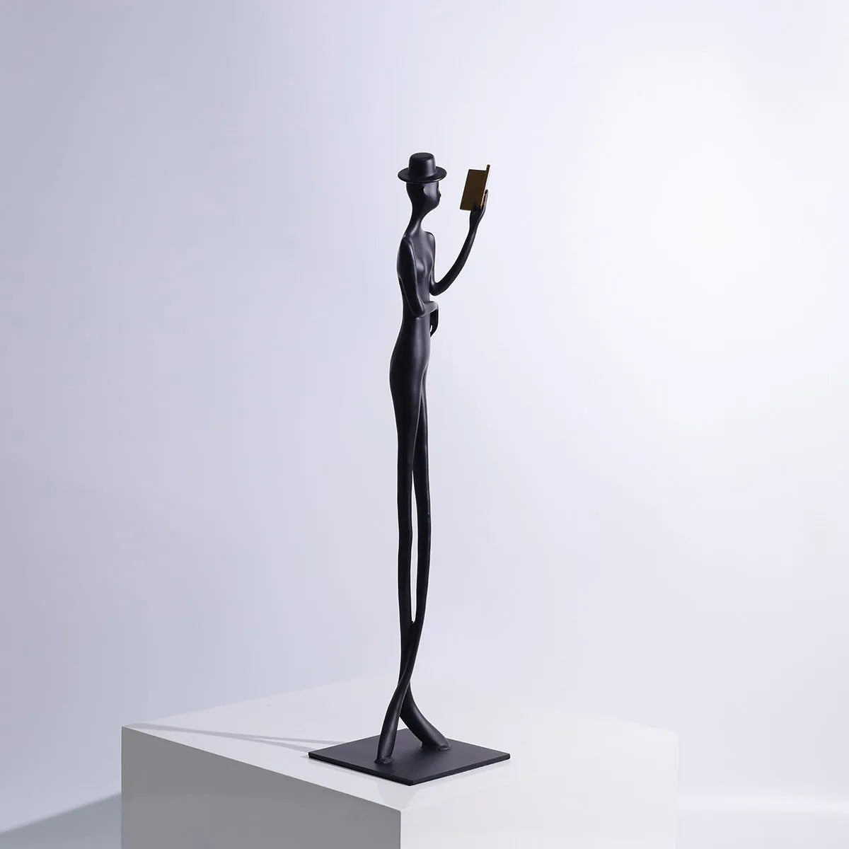 Black cast aluminium desktop sculpture of a woman reading, modern simplicity style, 51cm tall.