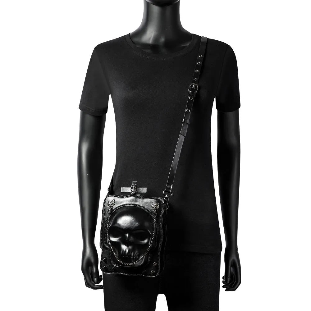 Black mini square crossbody bag with detailed skull embossing, rivets, and a shoulder strap.