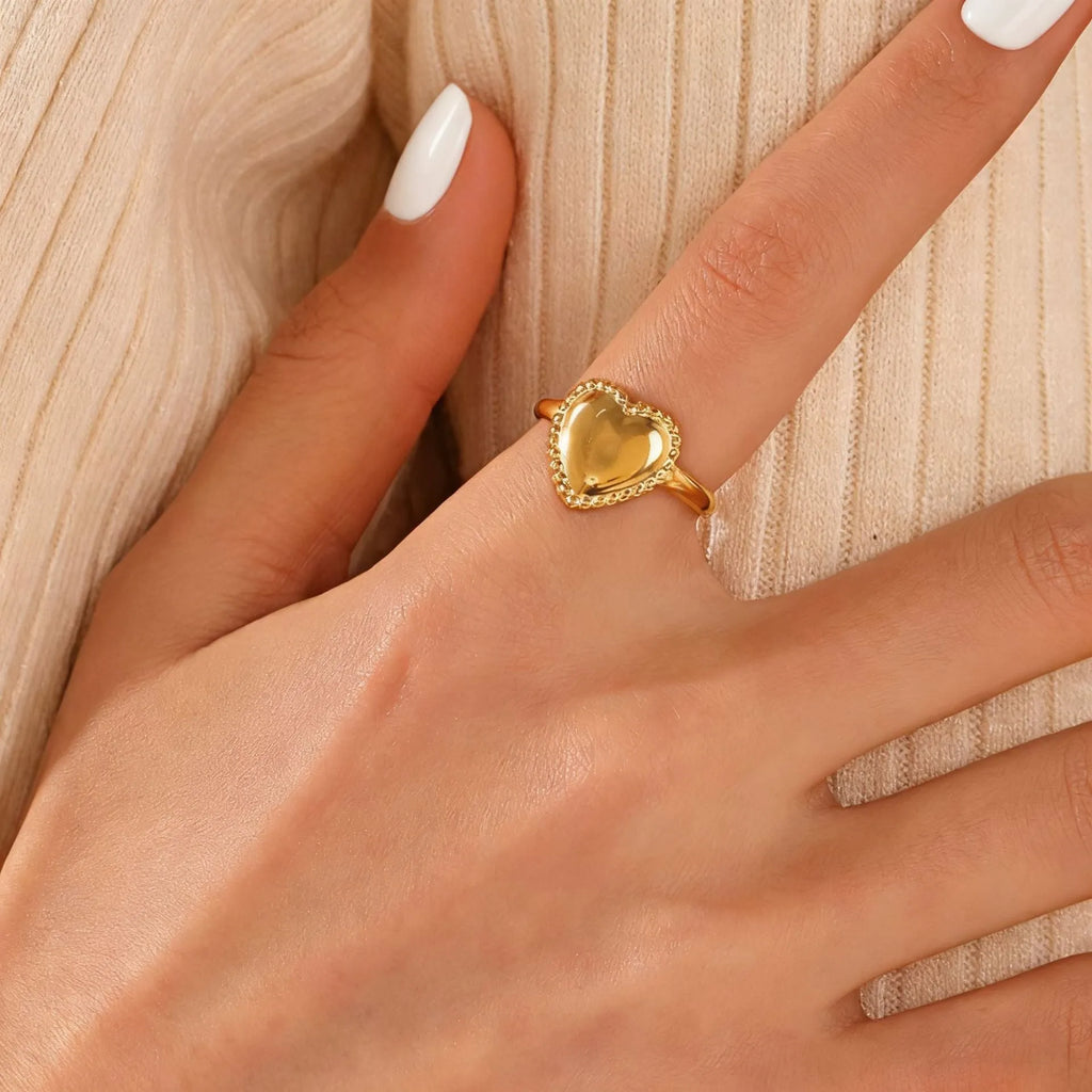 Adjustable stainless steel heart ring with electroplated gold finish on plain background