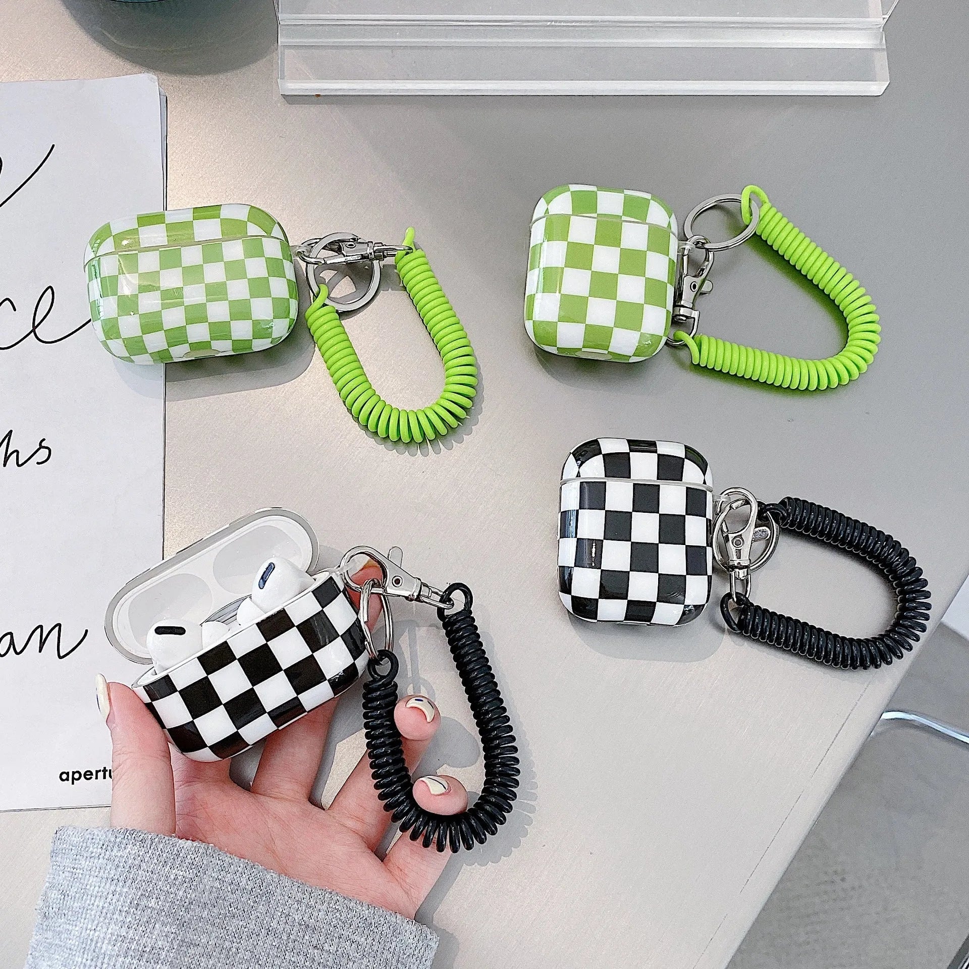 Black and green checkerboard lattice pattern TPU hard shell case covers for AirPods with optional lanyard and pendant attachments.