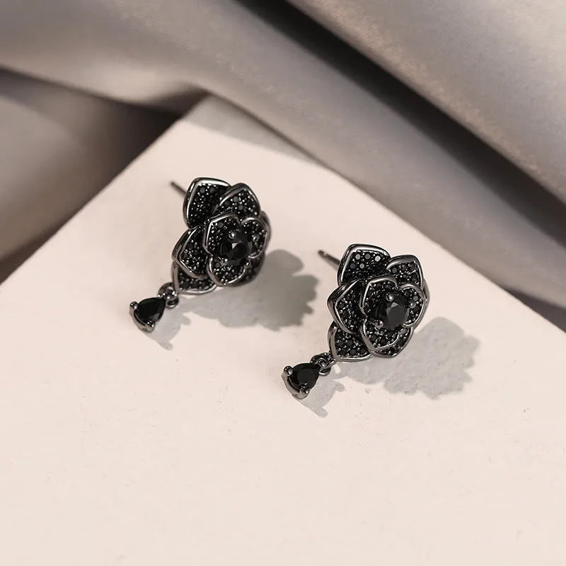 Close-up of women's black rose zircon flower stud earrings with 18K gold plating.