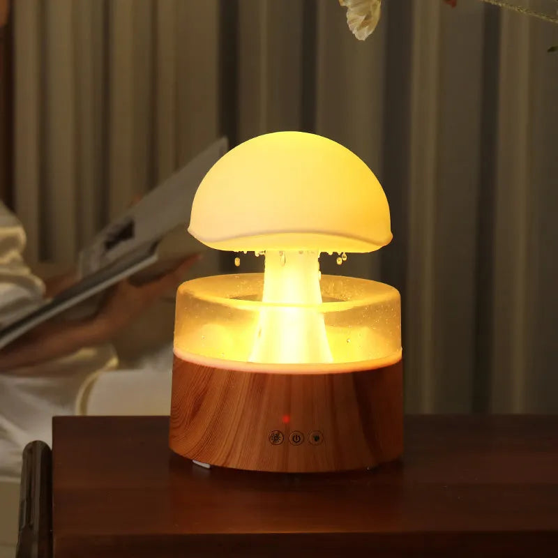 White rain cloud shaped ultrasonic humidifier and aromatherapy diffuser with coloured lights on a wooden table.