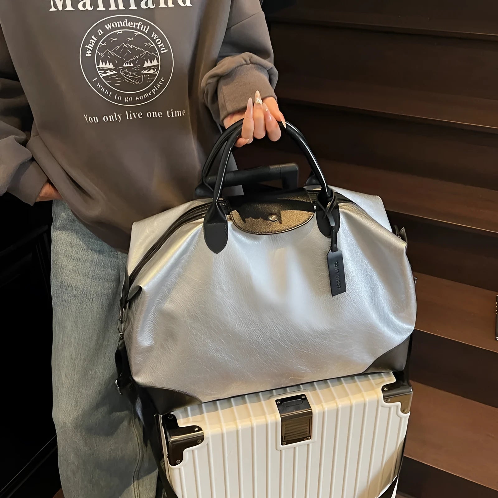 Women's hand-carry travel bag in black or silver with 36-55 litre capacity and PU material construction