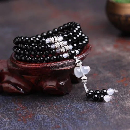 Natural black agate 108 bead bracelet with 8mm geometric beads on a wrist.