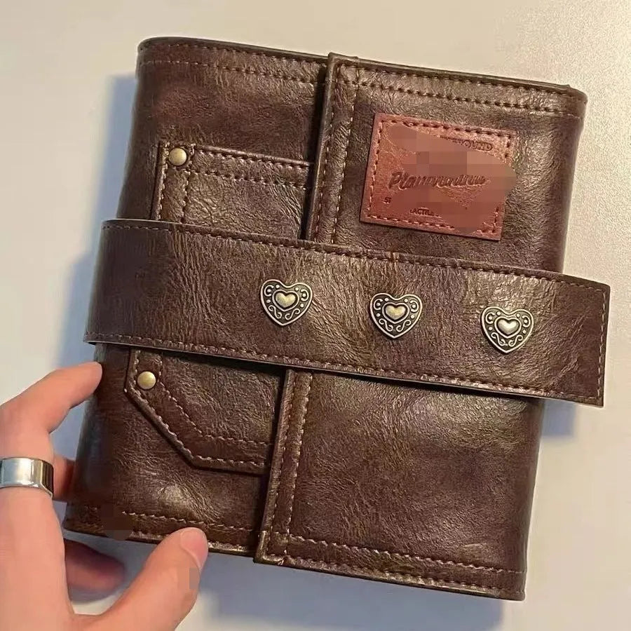 Brown A7 notebook with a leather buckle closure on a PU cover, showing loose-leaf binding