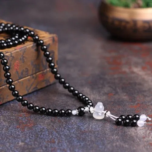 Natural black agate 108 bead bracelet with 8mm geometric beads on a wrist.