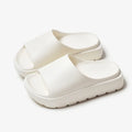 Women's beige thick-soled beach slippers with a fish mouth design on a wooden floor.