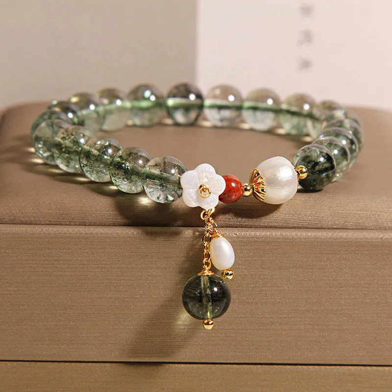 Green phantom quartz crystal bracelet for women with a small white shell flower accent.