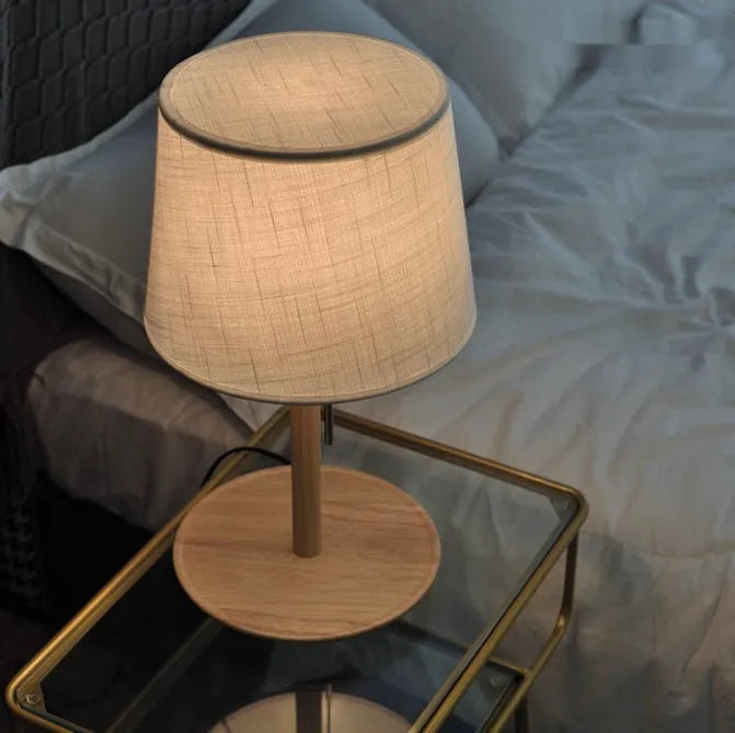 Walnut-coloured solid wood desk lamp with a white fabric lampshade and a black cord switch