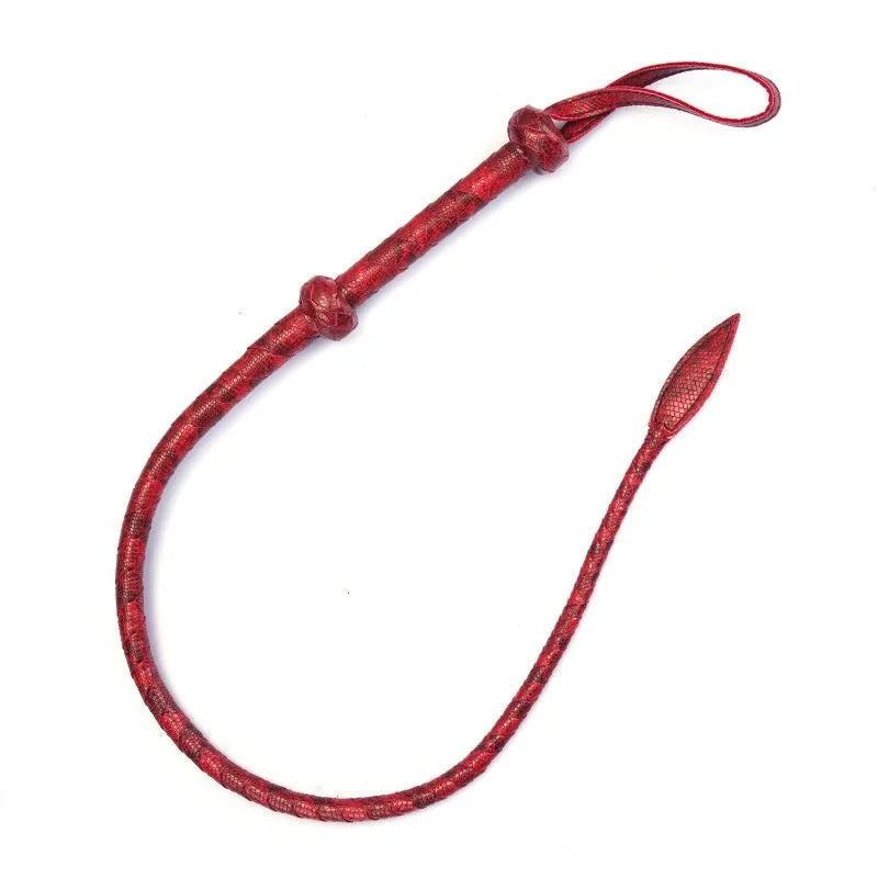 Red PU willow leaf whip for BDSM training and role play, lying on a surface.