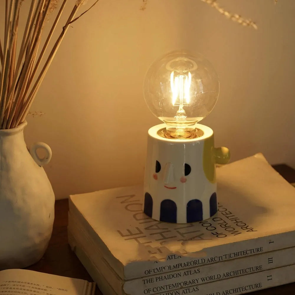 Handmade ceramic bedside lamp with a creative ball headlight design on a wooden table.