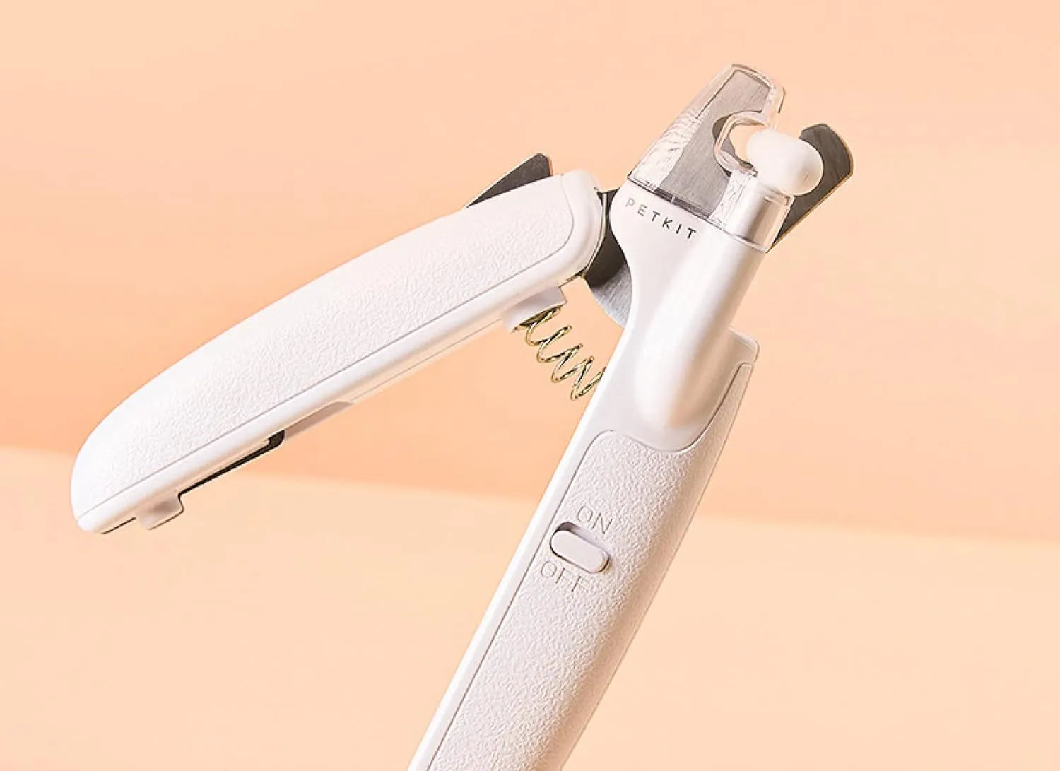White pet nail clippers with LED light, transparent guard, and nail file on a grey background.